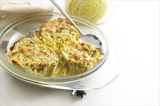 Chinese or napa cabbage gratinated in a glass casserole on a light gray table, healthy cooking,