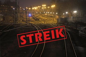 German text Streik (meaning strike) over shiny and curving railway tracks at night in a cargo