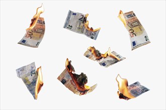 Burning money, collection of twenty and fifty euro banknotes with flames isolated on a white