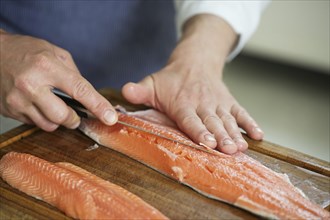 Char fish filleting, hands of the cook remove the bones with a thin fillet knife on a cutting