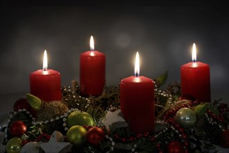 Candle light in the night, part of an Advent wreath with four red candles and Christmas decoration