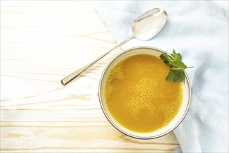 Carrot soup in a bowl on a light wooden table, healthy vegetable meal, recipe by professor Ernst