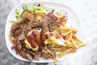 Doner kebab on a plate with French fries, salad and various sauces, popular fast food from Turkish