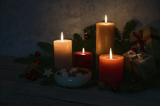 Candlelight in the dark, four advent candles, cinnamon star cookies and fir branches as decoration