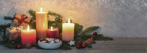 Advent candles in warm colors, cinnamon stars, Christmas decoration and fir branches on a rustic