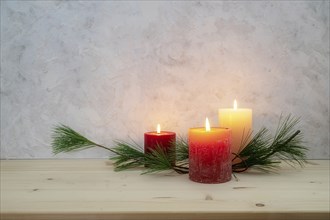 Three candles lit for the third Advent, pine branch as a simple, minimal decoration on a light