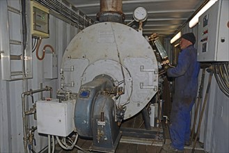 GREYMOUTH, NEW ZEALAND, MAY 15, 2020: A boiler operator works on a portable diesel generator fitted