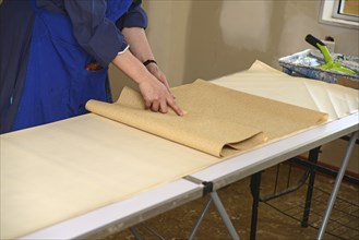 A woman rolls up some glued wallpaper, ready to decorate a bedroom