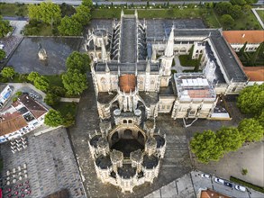 Aerial view of a Gothic abbey with elaborate architecture surrounded by trees and squares, aerial