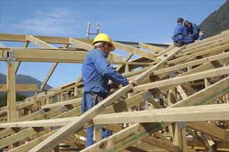 Builders working on the roof of a large house