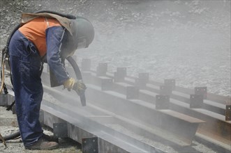 Tradesman sandblasting I beams for building project