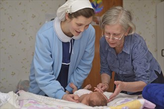 A senior midwife checks a newborn baby with her mother