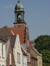 Traditional houses and a church tower with red tiled roofs under a clear sky, friedrichstadt,