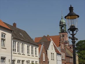 A traditional street with historic houses, a church tower and a lamppost on a sunny summer's day,