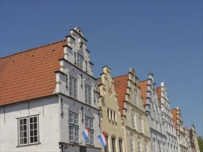 Historic houses with Dutch flags and distinctive gables under a blue sky, friedrichstadt,