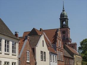 Church tower and old houses with red tiled roofs under a blue summer sky, friedrichstadt,