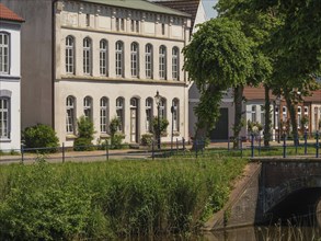 Beautiful riverside building with well-kept garden and trees next to a small canal, friedrichstadt,