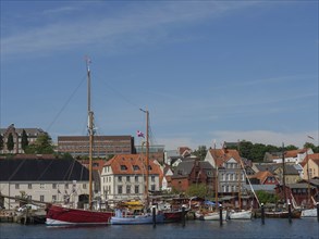 Idyllic harbour with sailing ships and charming old buildings on the shore under a blue sky,