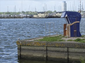 View of the harbour with calm water and a relaxing deckchair on the shore, Schleswig,