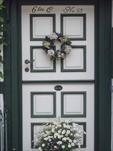 A beautifully decorated door with a wreath of flowers and a flower box underneath, Schleswig,