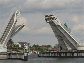 Bascule bridge over the harbour in open state, with boats and buildings along the shore under a