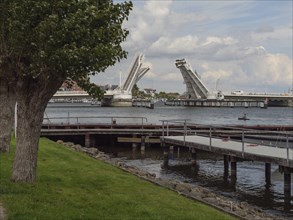 Rising bascule bridge over a harbour under a partly cloudy sky, Kappeln, Schleswig-Holstein,