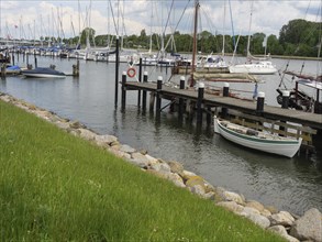 Boats at the dock in a quiet harbour surrounded by grass and a green waterfront, Kappeln,