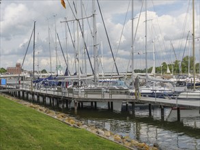 Sailboats dock at the marina in a partly cloudy sky with manicured lawn, Kappeln,