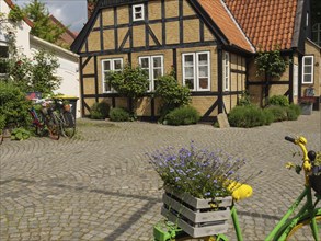 Half-timbered house with blooming flowers and a bicycle on a cobblestone street, Kappeln,