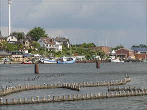 View of the harbour with fishing boats and buildings along the shore under a cloudy sky, Kappeln,