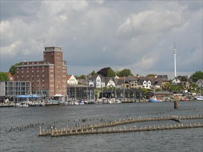 Town view with various buildings and boats on the waterfront under a cloudy sky, Kappeln,