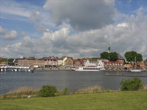 Panorama of a riverside town with historic buildings under a partly cloudy sky, Kappeln,