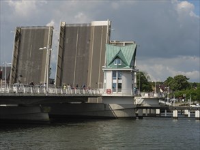 An open bridge next to a small watchtower over a river under a cloudy sky in a town, Kappeln,