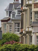 Row of townhouses with various architectural details and sloping roofs, surrounded by trees,