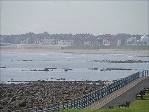 A stretch of coastline with a promenade and a view of a town in the background, Newcastle, England,