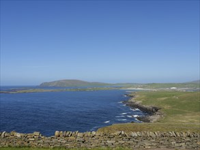 Extensive coastal landscape with green fields, stone walls and blue sky, Lerwick, Shetlands,