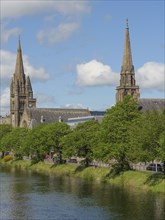 Church buildings and other architectural structures on the banks of a river, surrounded by trees