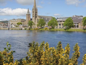 City view along the river with prominent churches and buildings and a bridge in the background,