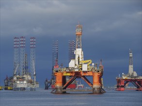 Several drilling platforms stand in the calm sea under an overcast sky, inverness, Scotland, United