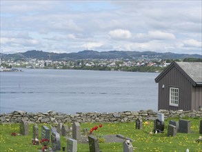 Tranquil river landscape with a cemetery and a view of the city in the distance, Haugesund, norway