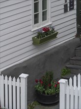 White house wall with flower arrangement and white fence that conveys the feeling of spring,