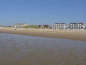 Building on a vast sandy beach with calm sea and blue sky in the background, de haan, belgium