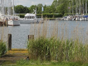 Harbour with several boats and sailing ships, surrounded by reeds and plants by the water, Arnis,