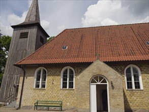 Small brick church with wooden tower and red tiled roof in summer, Kappeln, Schleswig-Holstein,