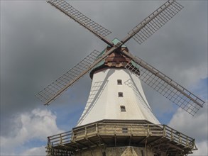 A large traditional windmill with wooden sails in front of a cloudy sky, Arnis, Schleswig-Holstein,