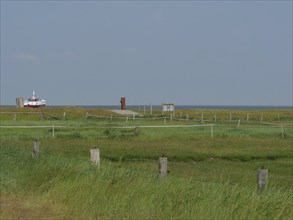 Green scenic meadow with a ship in the background and clear sky, Hallig Hooge, schleswig-holstein,