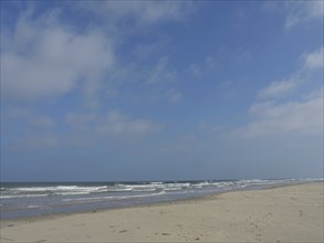 Spacious beach with a view of the calm sea and a partly cloudy sky, Juist, East Frisia, Germany,