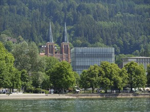 Two church towers and a modern building in a green, wooded setting by the lake, Lindau, Lake