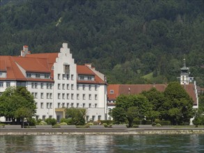 Large building with red roofs in front of a wooded hill directly on a lake, Lindau, Lake Constance,