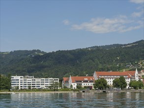 Town view with modern buildings and traditional houses on the lakeshore in front of green